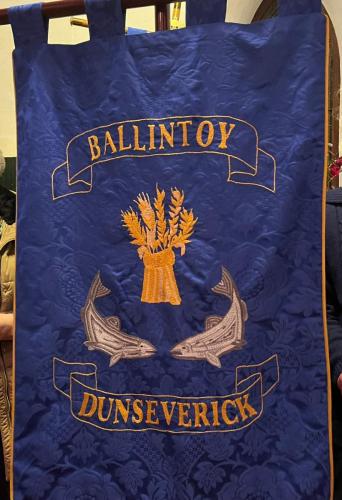 The salmon and barley sheaf on one side of the banner reflecting their farming and fishing communities, the harvests of the land and sea and God's providence.